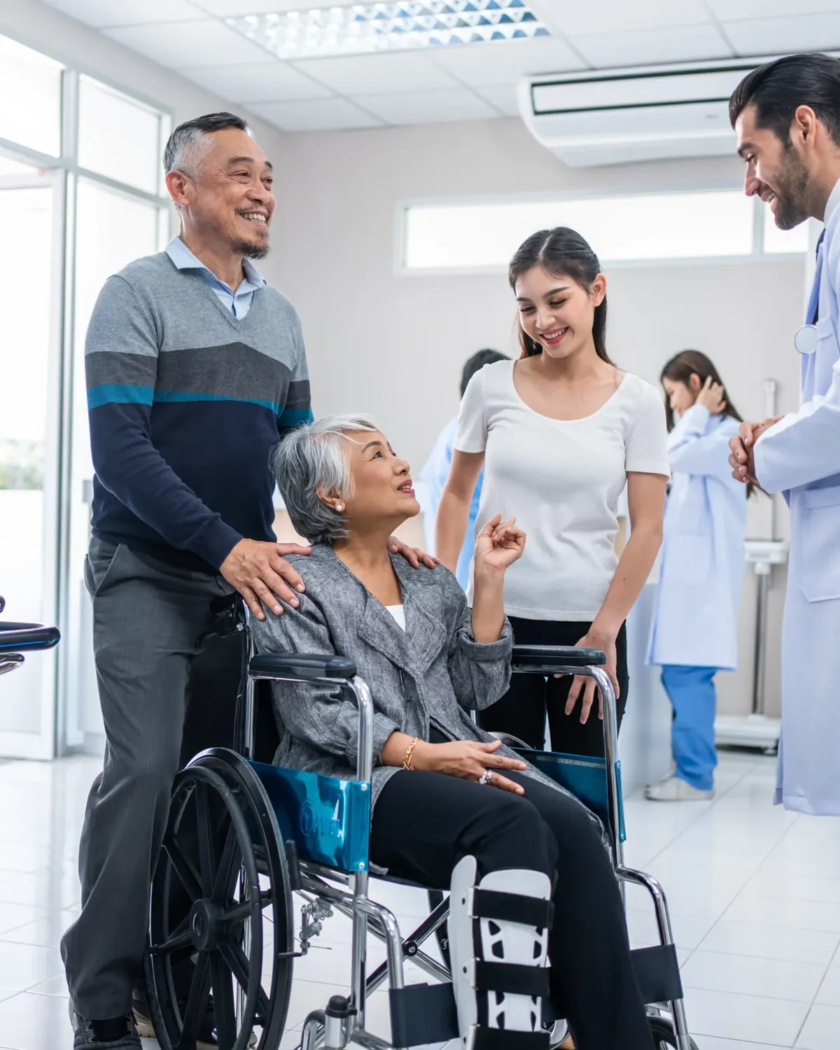 A doctor walking a patient in a wheelchair through the practice hallway